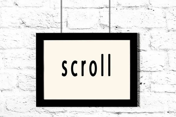 碑文のスクロールと白いレンガの壁にぶら下がっている黒いフレーム — ストック写真