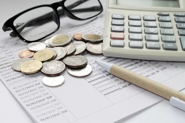 Pièces de monnaie, lunettes, calculatrice et stylo sur le livret de compte d'épargne — Photo