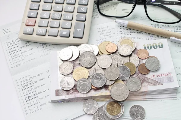 Coins, money, calculator, glasses and pen on savings account passbook