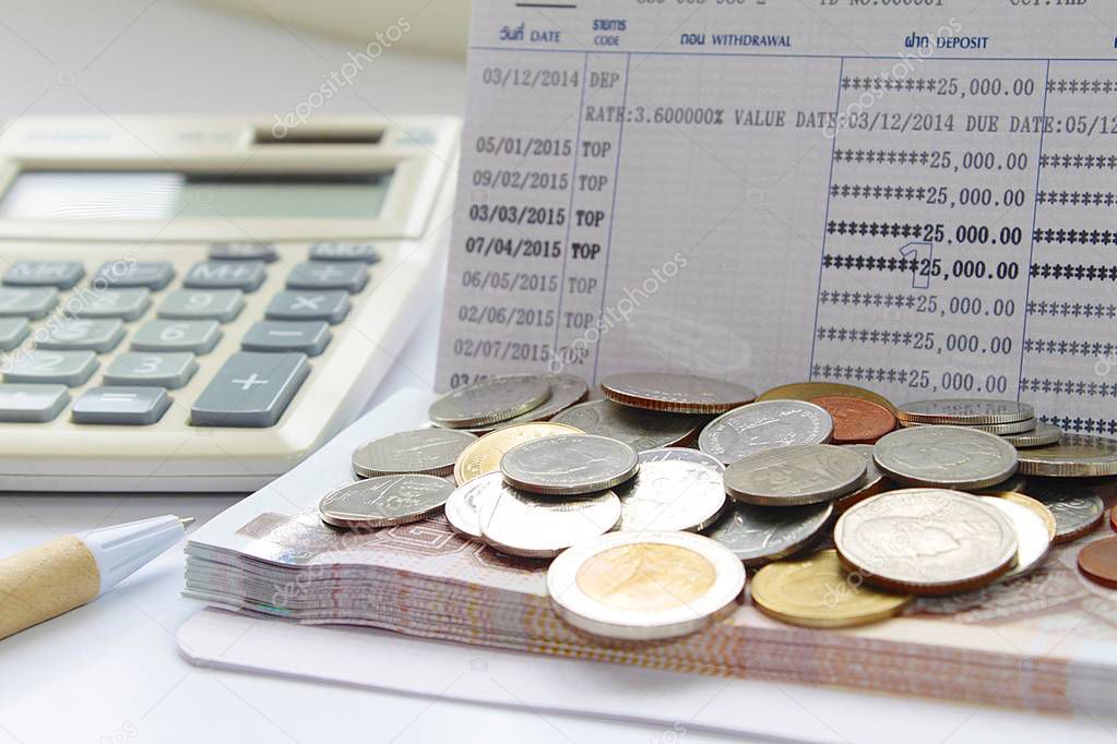 Coins and Thai Baht money on savings account passbook, calculator and pen
