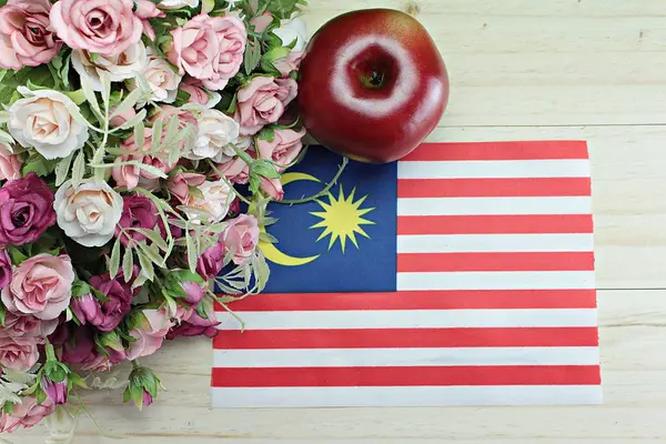 Malaysia flag, apple and flower on wood background — Stock Photo, Image