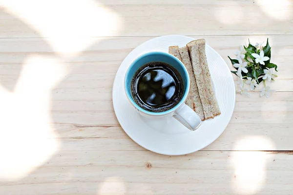 Cup of coffee, fresh tuna sandwich and white flowers on wood background