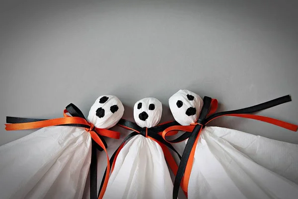 Tres fantasmas de Halloween DIY hechos de papel de tejido blanco, cinta negra y naranja sobre fondo gris — Foto de Stock