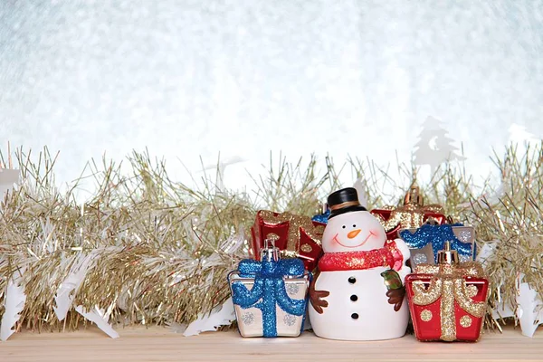 Милий сніговик, різдвяна подарункова коробка або подарунки, золотий стример або мішура на дереві, срібний блиск фону — стокове фото