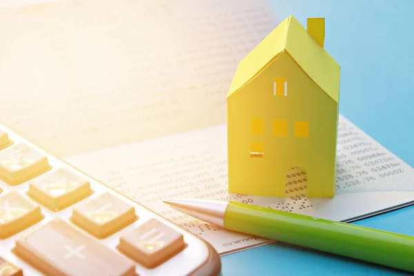 Megtakarítási számla, Betétkönyv, számológép, toll és sárga papír a ház a kék háttér — Stock Fotó