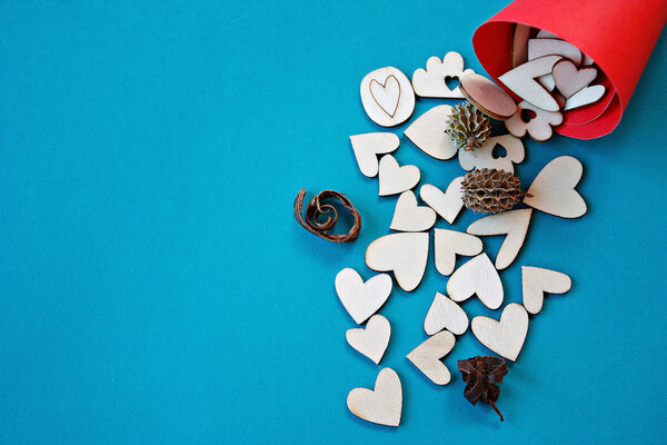 Wooden hearts in a red craft paper cornet on blue background