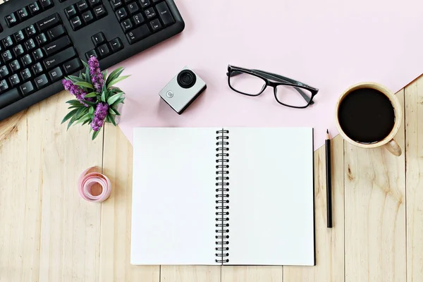 Flat lay style of office workspace desk with blank notebook paper, computer keyboard, cup of coffee and accessories — Stock Photo, Image