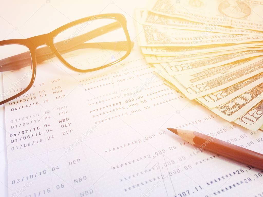 Pencil, eyeglasses, money and savings account passbook or financial statement on white background