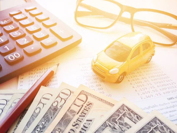 Modelo de coche miniatura, lápiz, dinero, calculadora, anteojos y libreta de la cuenta de ahorros o estado financiero sobre fondo blanco — Foto de Stock