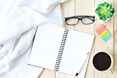 Yat veya battaniye, Açık boş defter kağıt, kahve fincanı ve gözlük ahşap arka plan üzerinde beyaz üstten görünüm örme