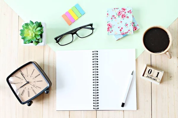 Top view or flat lay of open notebook paper, accessories, cube calendar and coffee cup on wooden background, ready for adding or mock up — Stock Photo, Image