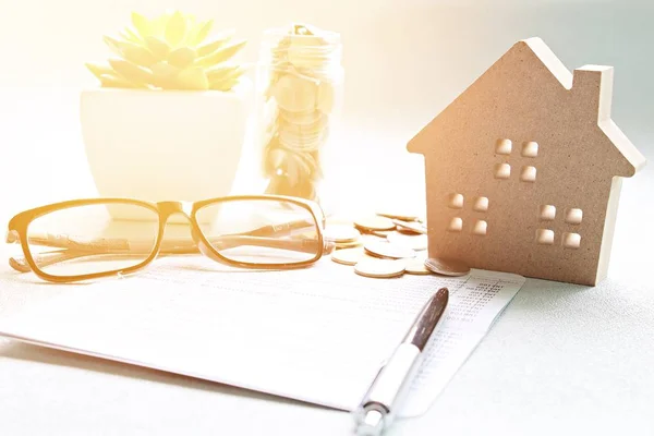 Wood house model, saving account book or financial statement and coins on office desk table — Stock Photo, Image