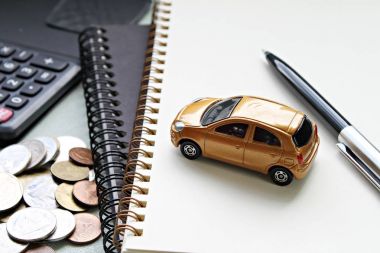 Minyatür araba modeli, kalem, defter belgeleri, hesap makinesi ve sikkeler üzerinde ofis masaları