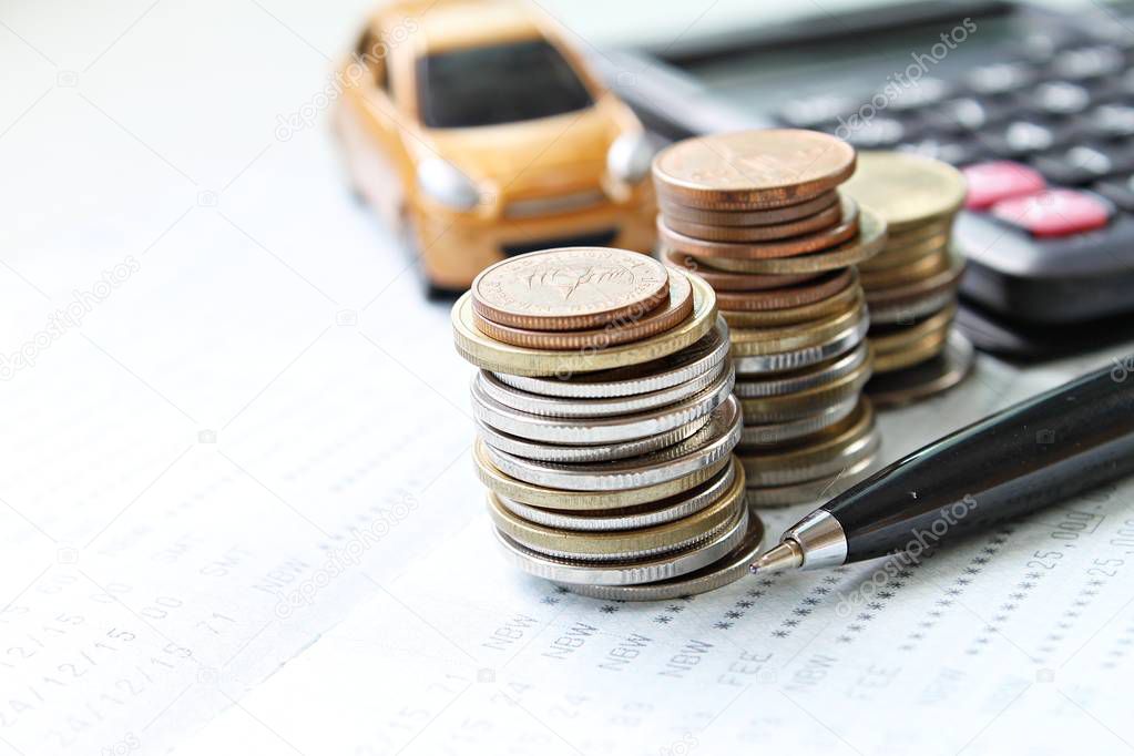 Miniature car model, calculator, coins and saving account book or financial statement on office desk table