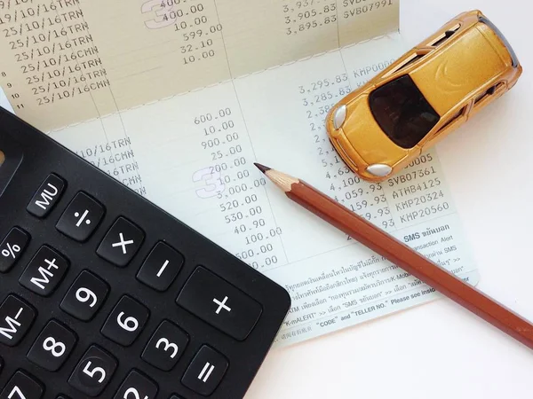 Miniature car model, calculator and saving account book or financial statement on office table