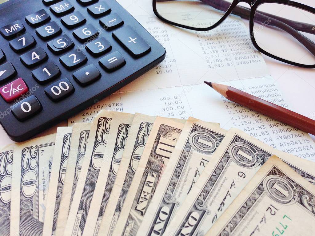 Dollar money, calculator and saving account book or financial statement on office table