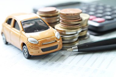 Minyatür araba modeli, sikke yığını, hesap makinesi ve Resepsiyon masasında hesabına kitap ya da mali tablo kaydetme