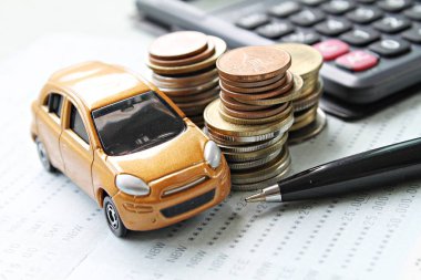 Minyatür araba modeli, sikke yığını, hesap makinesi ve Resepsiyon masasında hesabına kitap ya da mali tablo kaydetme