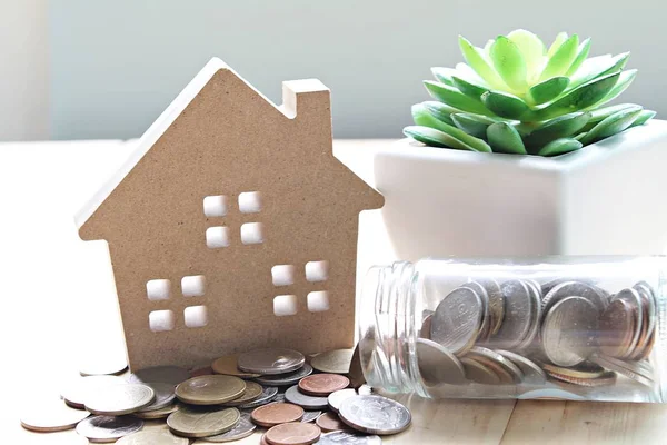 Modelo de casa de madera y monedas en mesa de escritorio —  Fotos de Stock