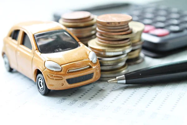 Миниатюрная модель автомобиля, стопка монет, калькулятор и книга сбережений или финансовая отчетность на столе — стоковое фото