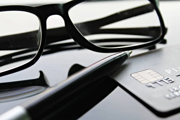 Carte de crédit, lunettes et stylo sur table de bureau — Photo