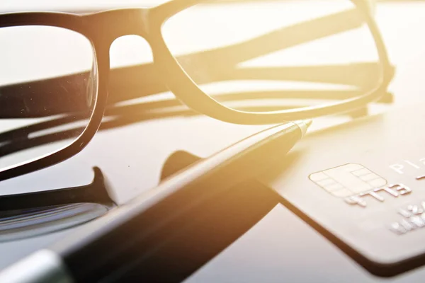 Carte de crédit, lunettes et stylo sur table de bureau — Photo