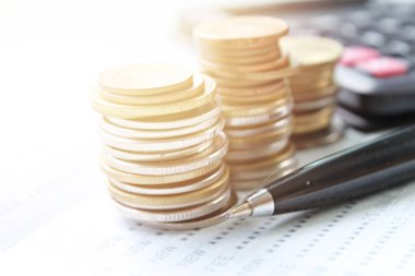 Sikke yığını, hesap makinesi, kalem ve ofis resepsiyon masası üzerinde hesap kitap ya da mali tablo kaydetme