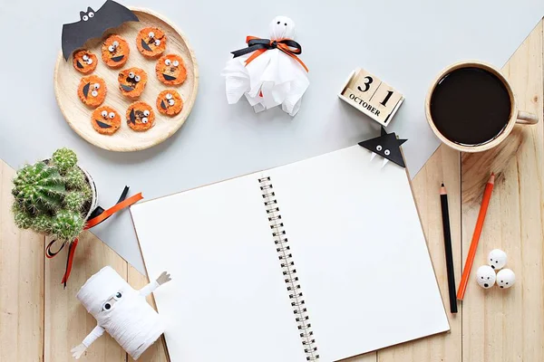 Mock up of open notebook, paper crafts, cube calendar, grilled carrots with scary face and coffee cup