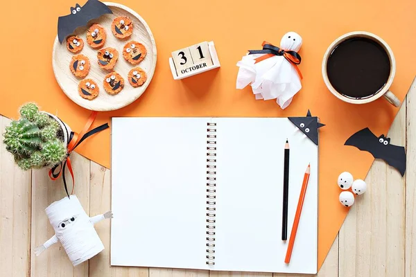 Mock up of open notebook, paper crafts, cube calendar, grilled carrots with scary face and coffee cup