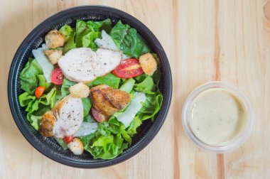 Tavuk ahşap masa çok lezzetli bir şeffaf plastik tabaklar, organik karışık yeşil salata