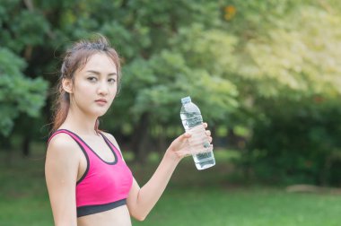 genç çekici kadın içme suyu parkta plastik şişe