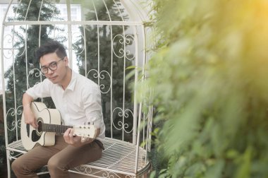 Neşeli gitarist. Gitar çalmak ve gülümseyen neşeli yakışıklı genç adam