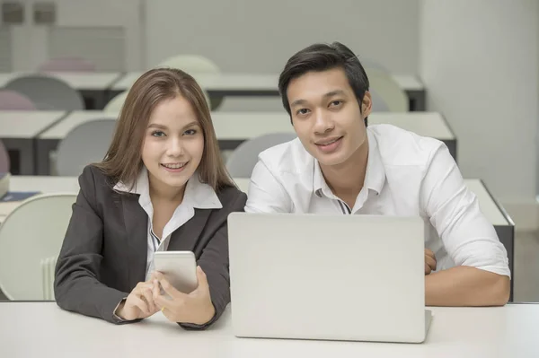 Geschäftsleute, die im Büro arbeiten und in die Kamera schauen — Stockfoto