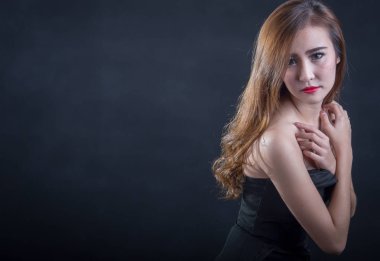 Güzel seksi kadın mükemmel ince gövde ve siyah arka plan üzerinde poz siyah elbiseli uzun kıvırcık saç. Stüdyo vurdu.