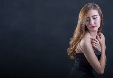 Güzel seksi kadın mükemmel ince gövde ve siyah arka plan üzerinde poz siyah elbiseli uzun kıvırcık saç. Stüdyo vurdu.