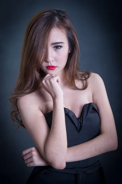 Hermosa mujer sexy con cuerpo delgado perfecto y pelo rizado largo en vestido negro posando sobre fondo negro. Captura de estudio . —  Fotos de Stock