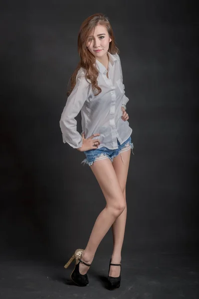 Портрет моделі красивих дівчат у білій сорочці та коротких джинсах у чистій шкірі красива та розумна концепція з чорним тканинним фоном — стокове фото