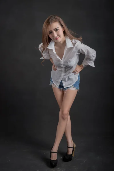 Porträtt av modell vackra flickor som bär vit skjorta och korta jeans i ren hud vacker och smart koncept med svart tyg bakgrund — Stockfoto