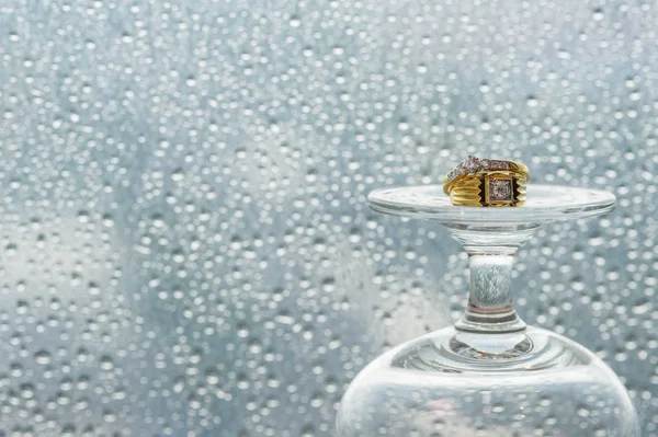 Anillo de boda en copa de champán delante del espejo con gotas de lluvia . Imagen de archivo