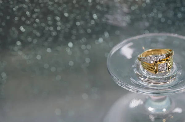 Anello nuziale su vetro di champagne di fronte a specchio con gocce di pioggia . Immagini Stock Royalty Free