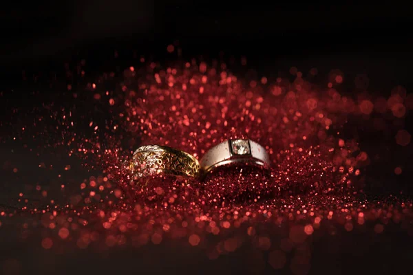 Gouden Trouwringen Met Rode Glitter Rode Bokeh Zwarte Achtergrond — Stockfoto