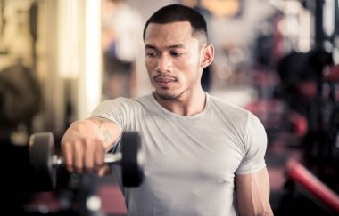 Onun vücut dumbbell Modern bir fitness merkezi ile eğitim kas Oluşturucu adam