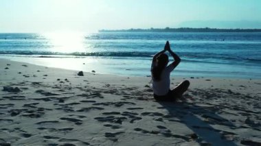 Bali sahilinde meditasyon yapan çekici bir kız.