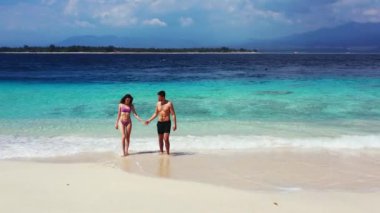 Genç ve güzel bir çiftin güzel bir okyanus videosunun yanında tatilin tadını çıkardığı tropik ada sahnesi. 