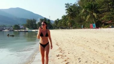 Tropik adanın kıyılarında mayo giymiş güzel genç bir kadının videosu. 