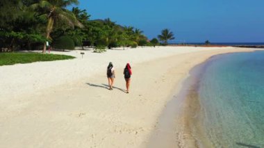 Sahilde yürüyen iki bayan arkadaşın görüntüsü. 