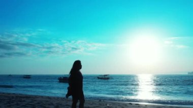 Kumsalda sırt çantalı bir kadın.