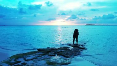 Gün batımında sahilde bir kadın silueti