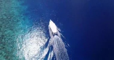 Teknenin turkuaz deniz suyundaki insanların hava görüntüsü.