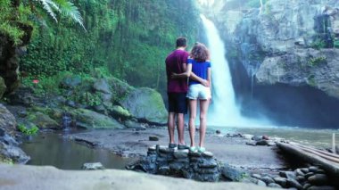 Romantik turistlerin, şelalenin yanında yan yana durdukları bir video.  